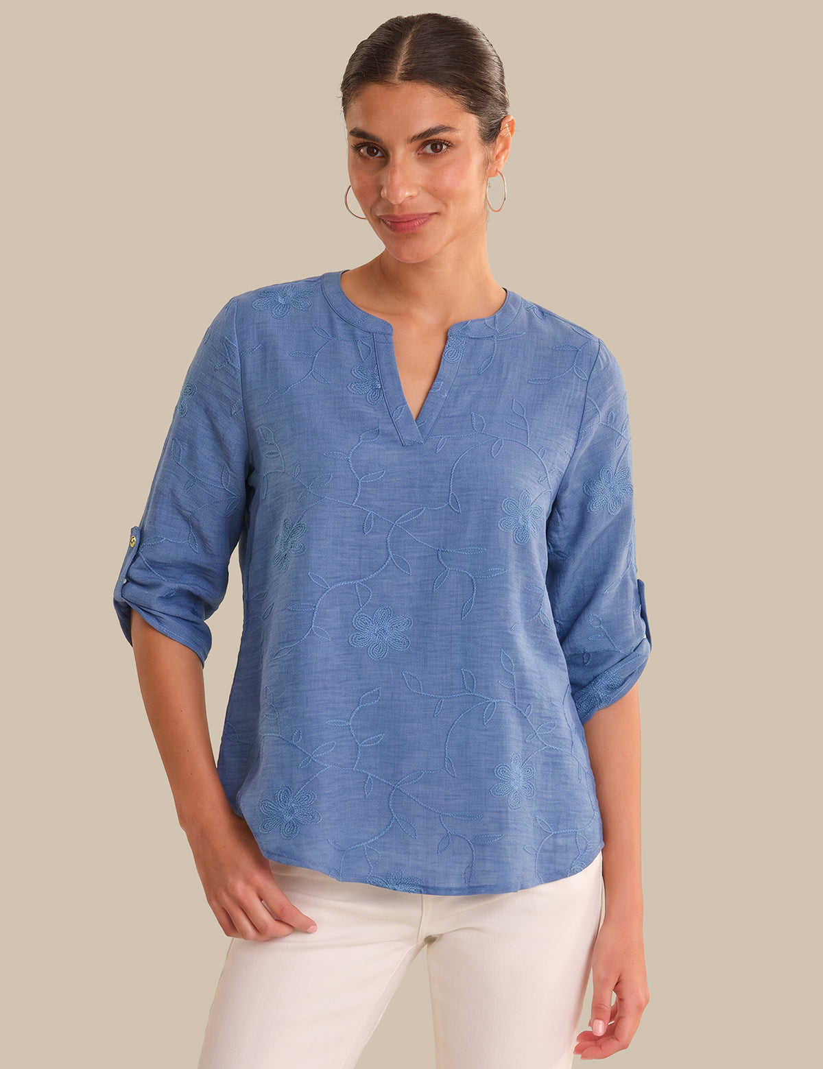 Woman wearing a blue shirt with rolled-up sleeves on a beige background
