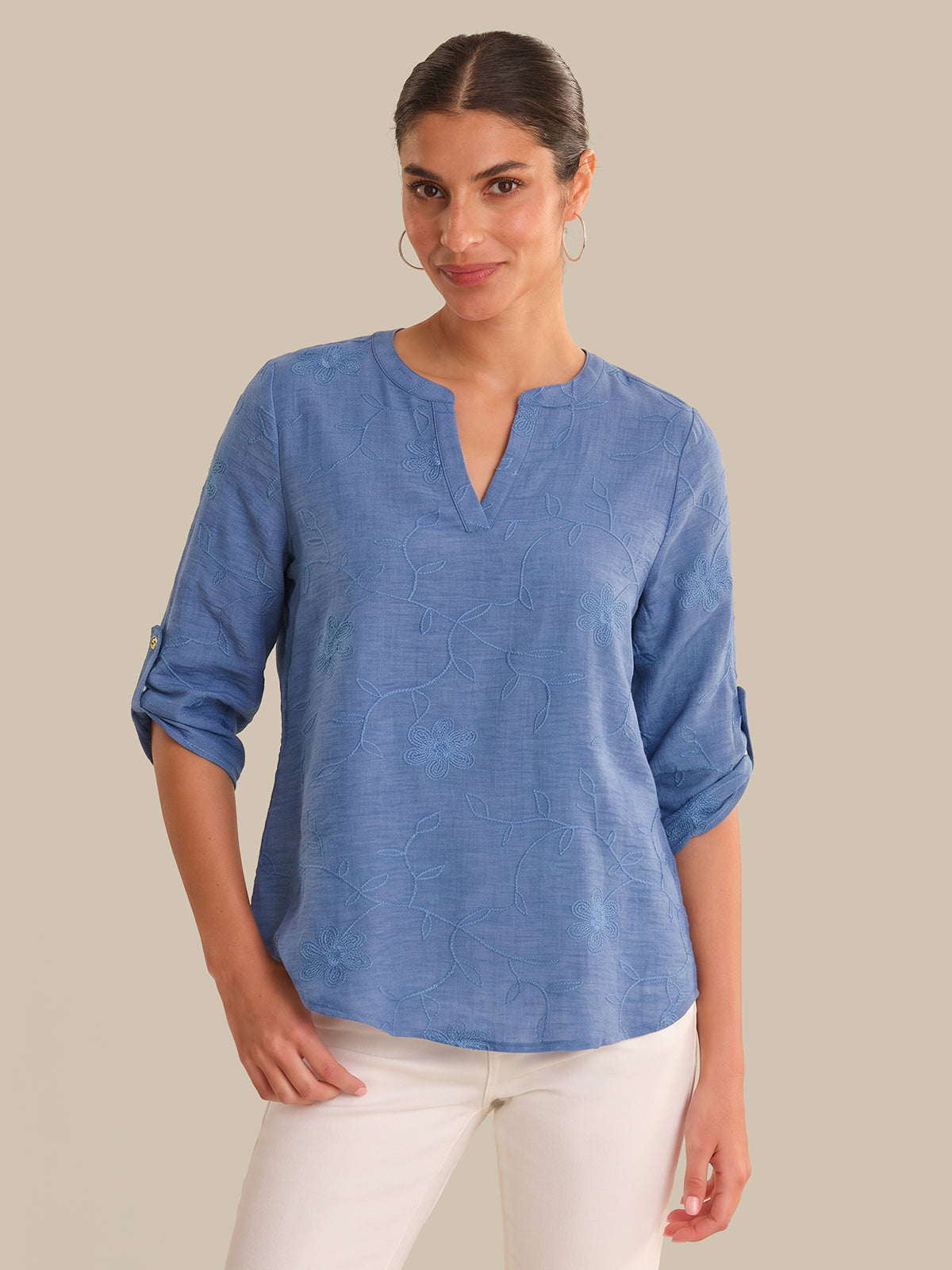 Woman wearing a blue shirt with rolled-up sleeves on a beige background