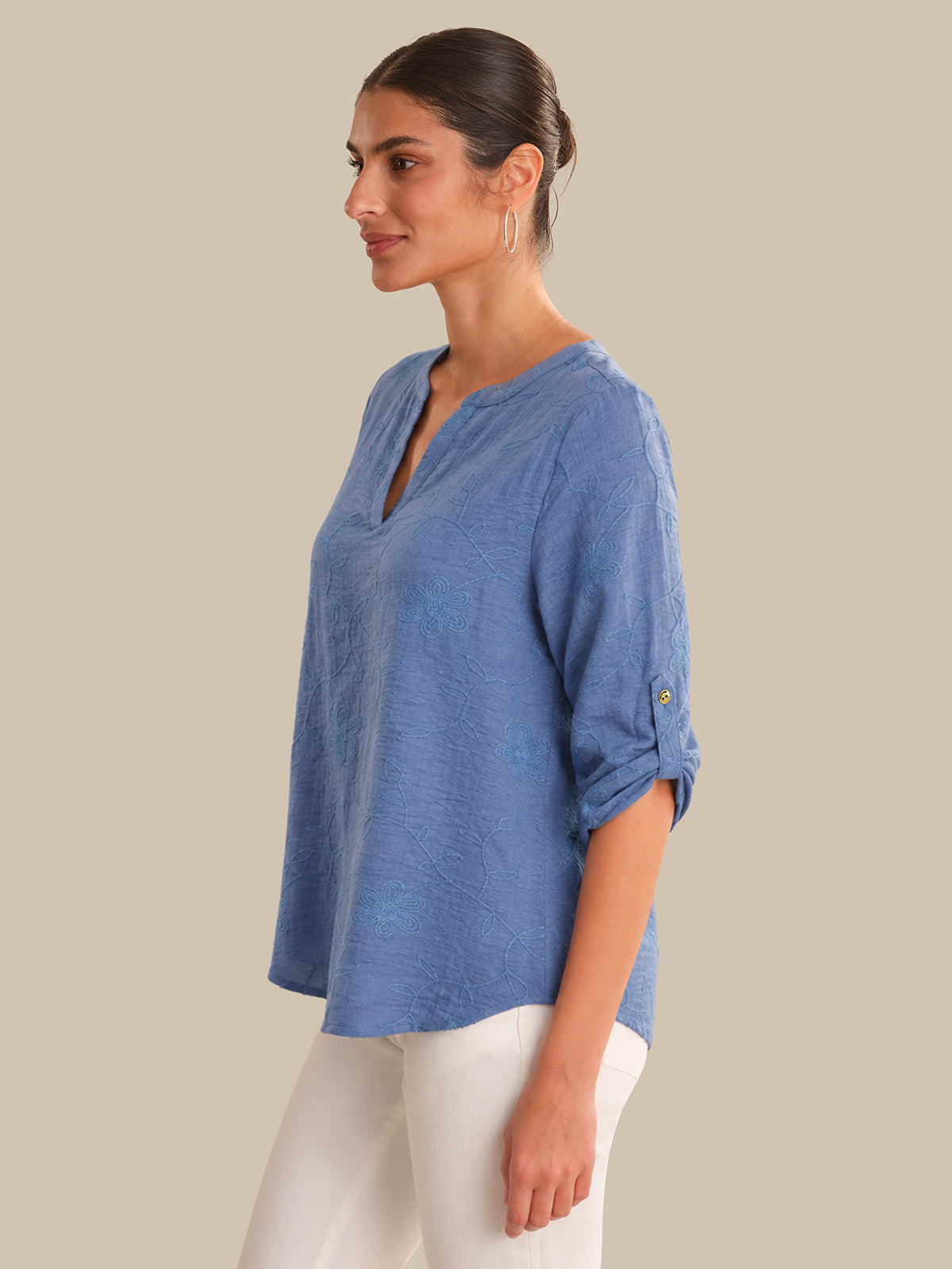 Woman wearing a blue top and white pants on a beige background