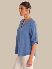 Woman wearing a blue top and white pants on a beige background