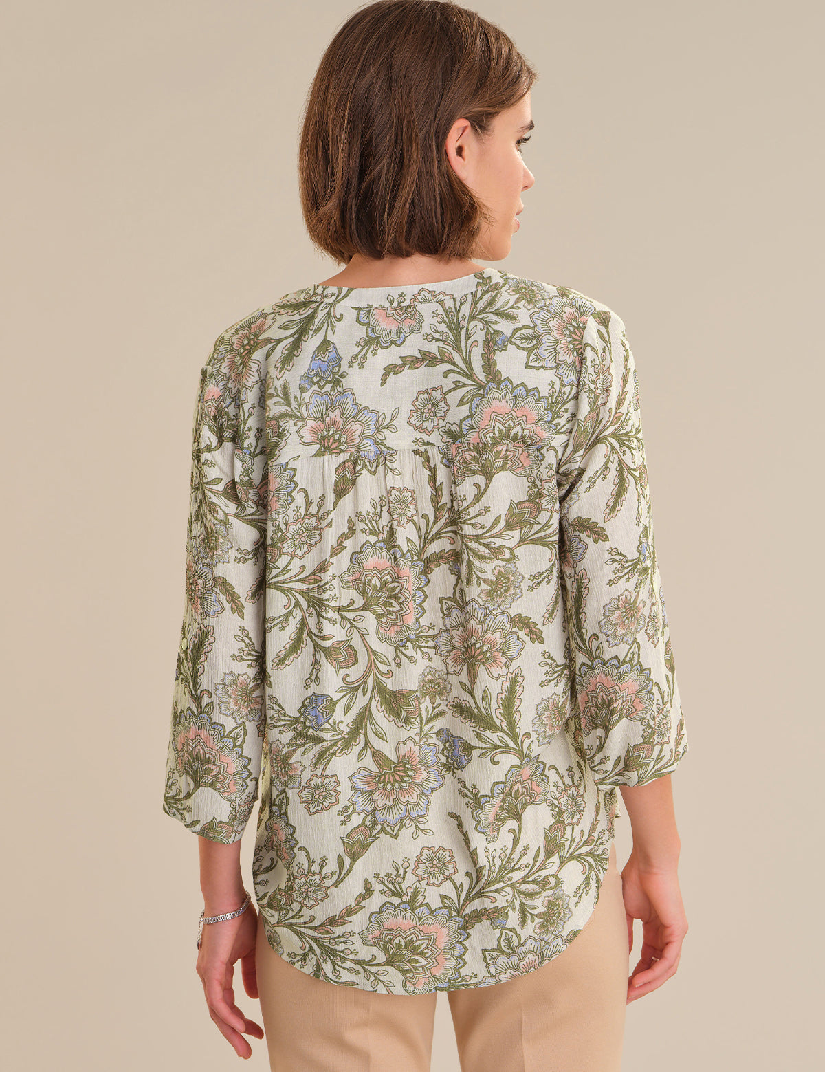 Woman wearing a floral patterned blouse against a beige background