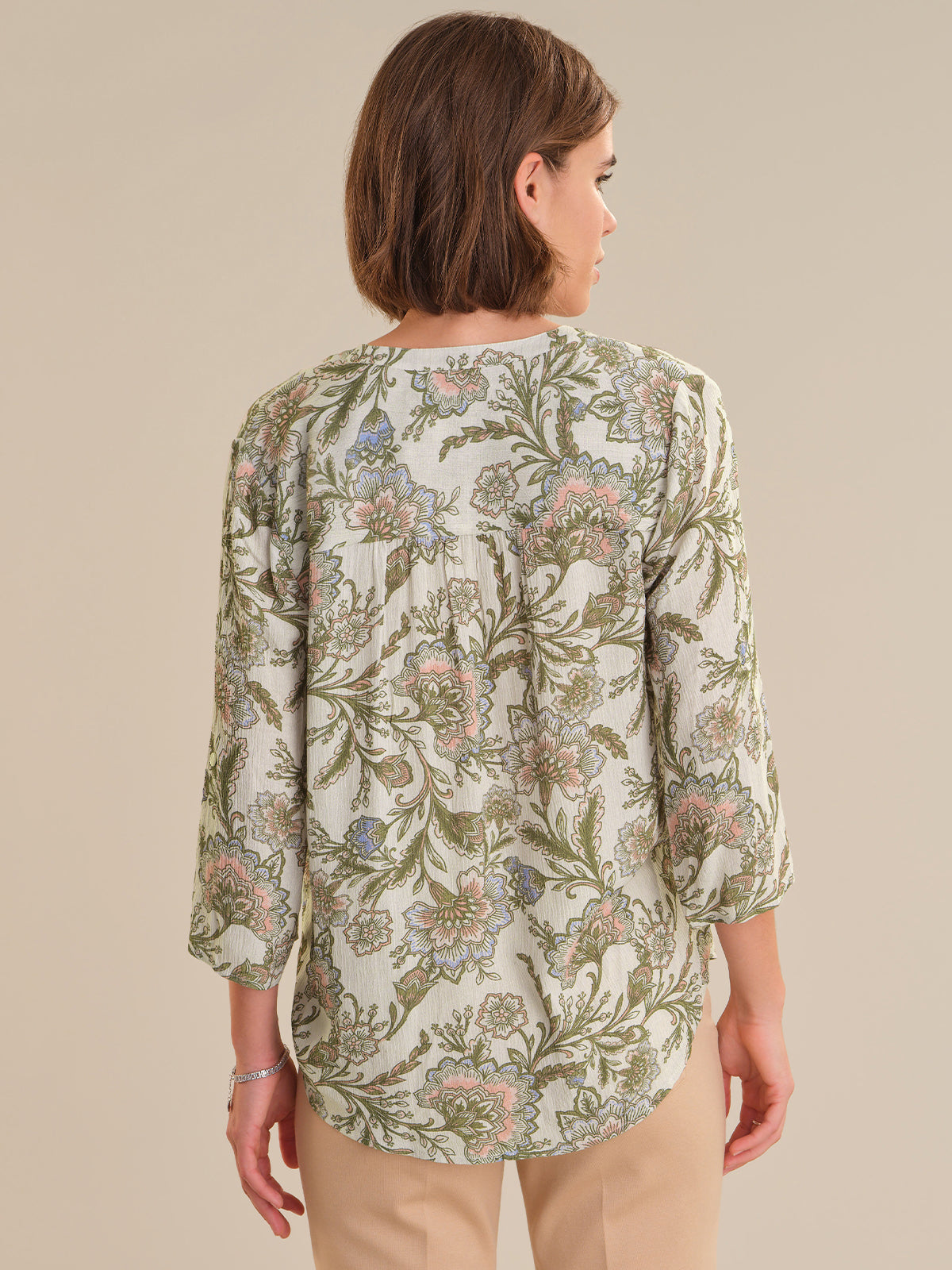 Woman wearing a floral patterned blouse against a beige background