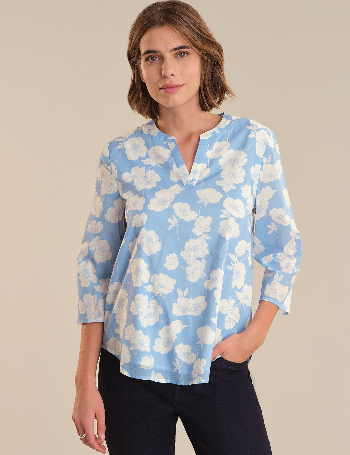 Woman wearing a blue floral blouse against a beige background
