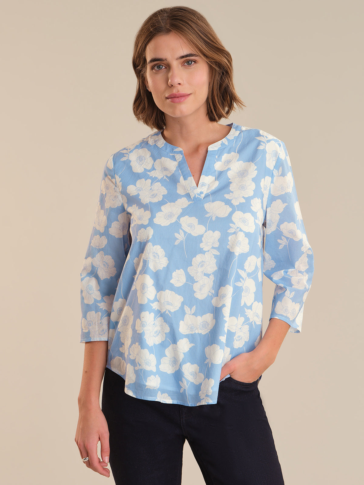 Woman wearing a blue floral blouse against a beige background