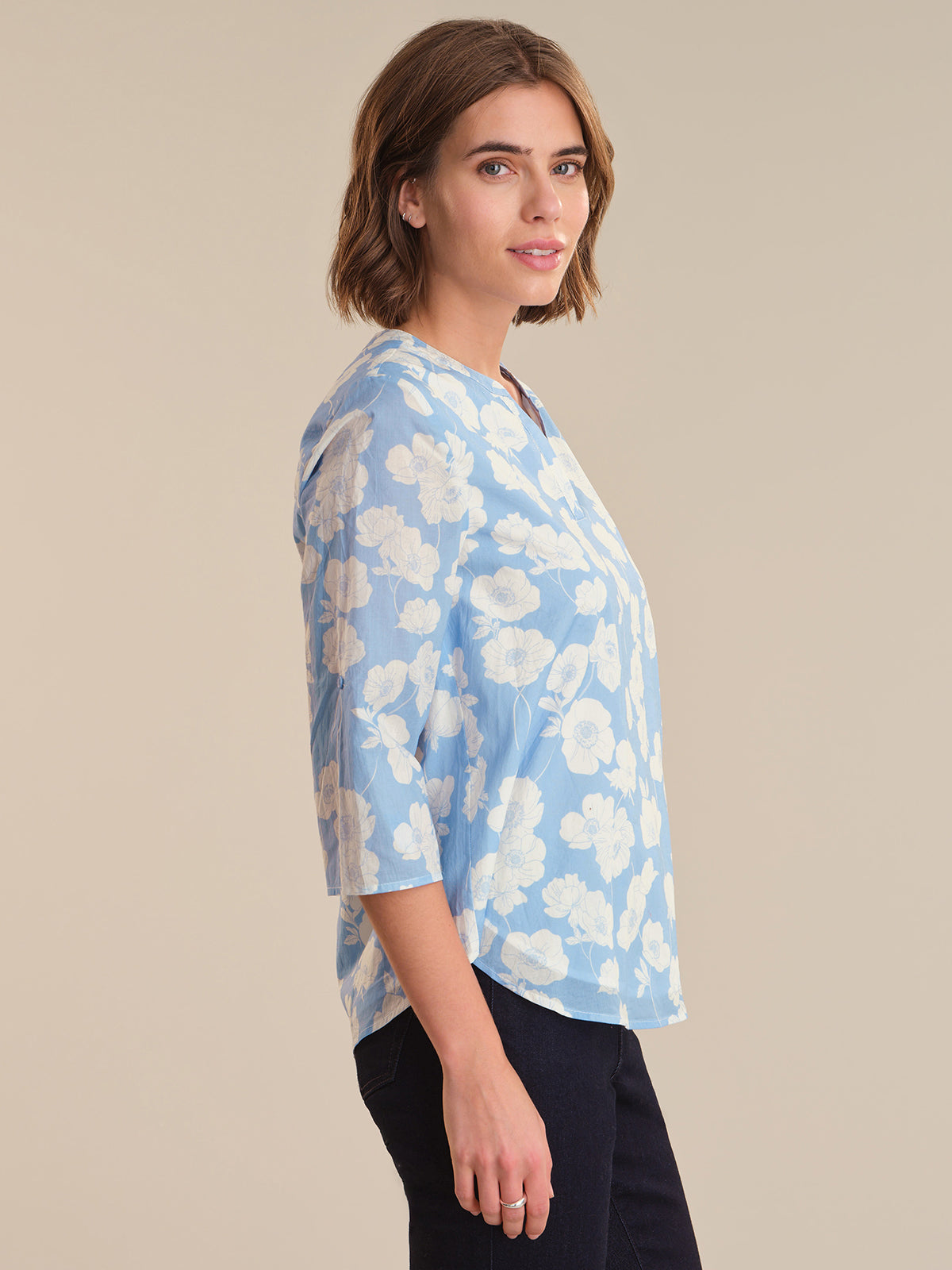 Woman wearing a light blue floral blouse against a beige background