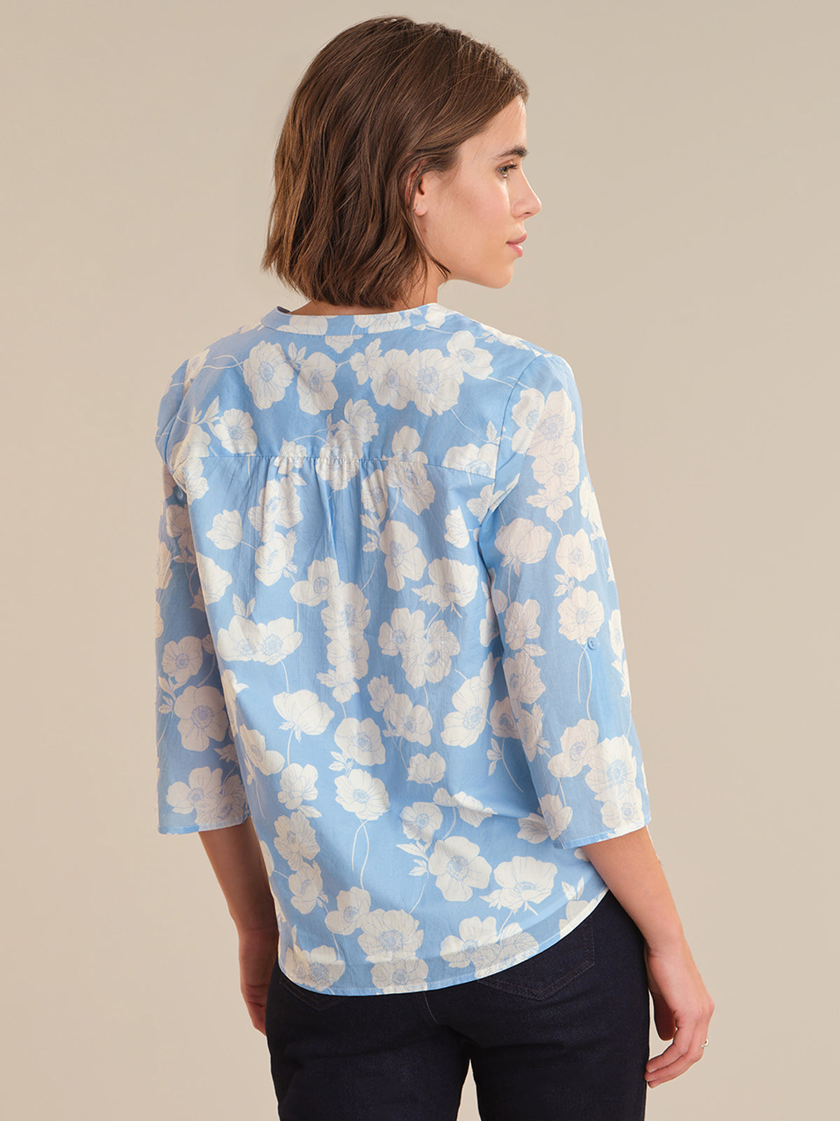 Woman wearing a blue floral blouse against a beige background