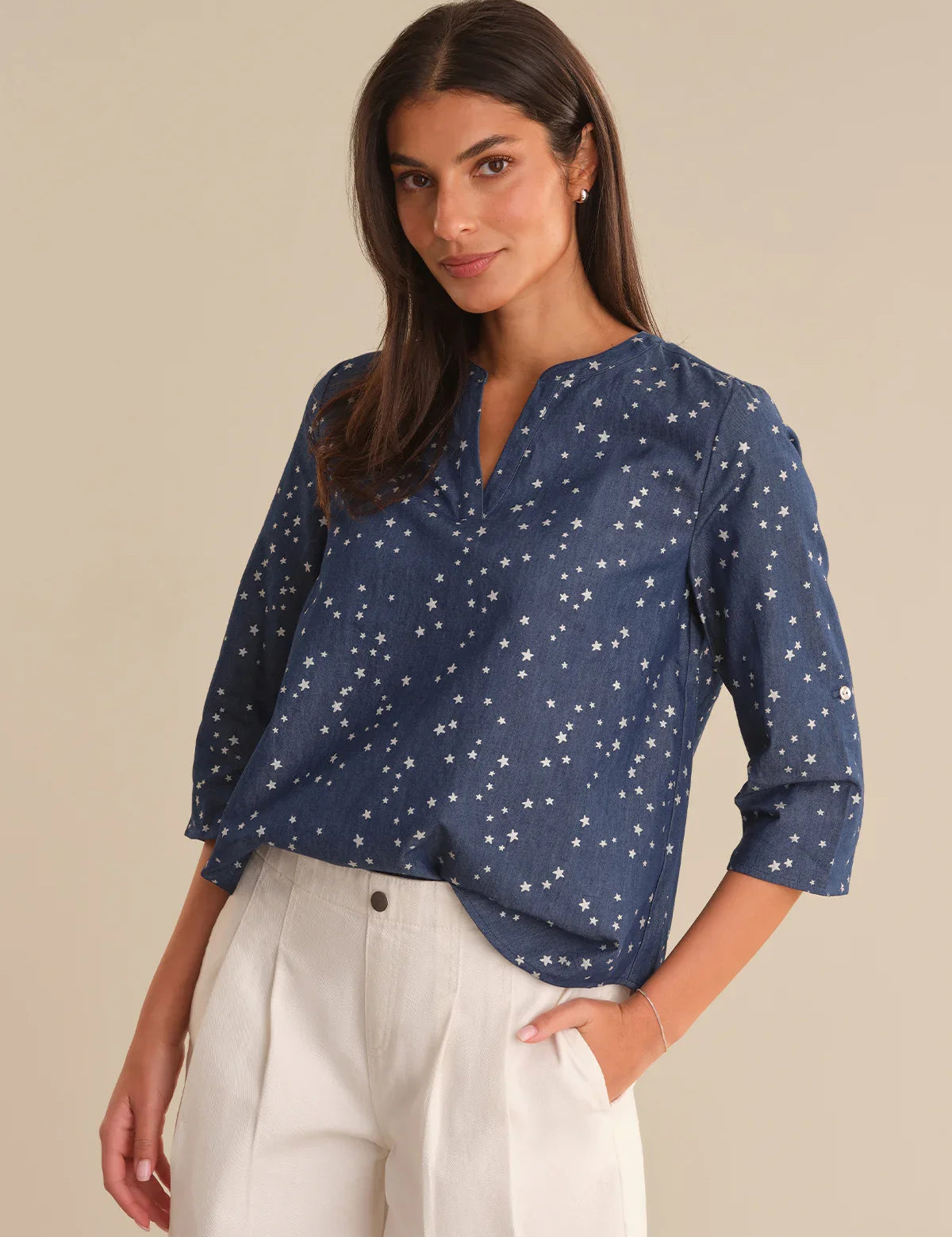 Woman wearing a blue star-patterned blouse against a beige background