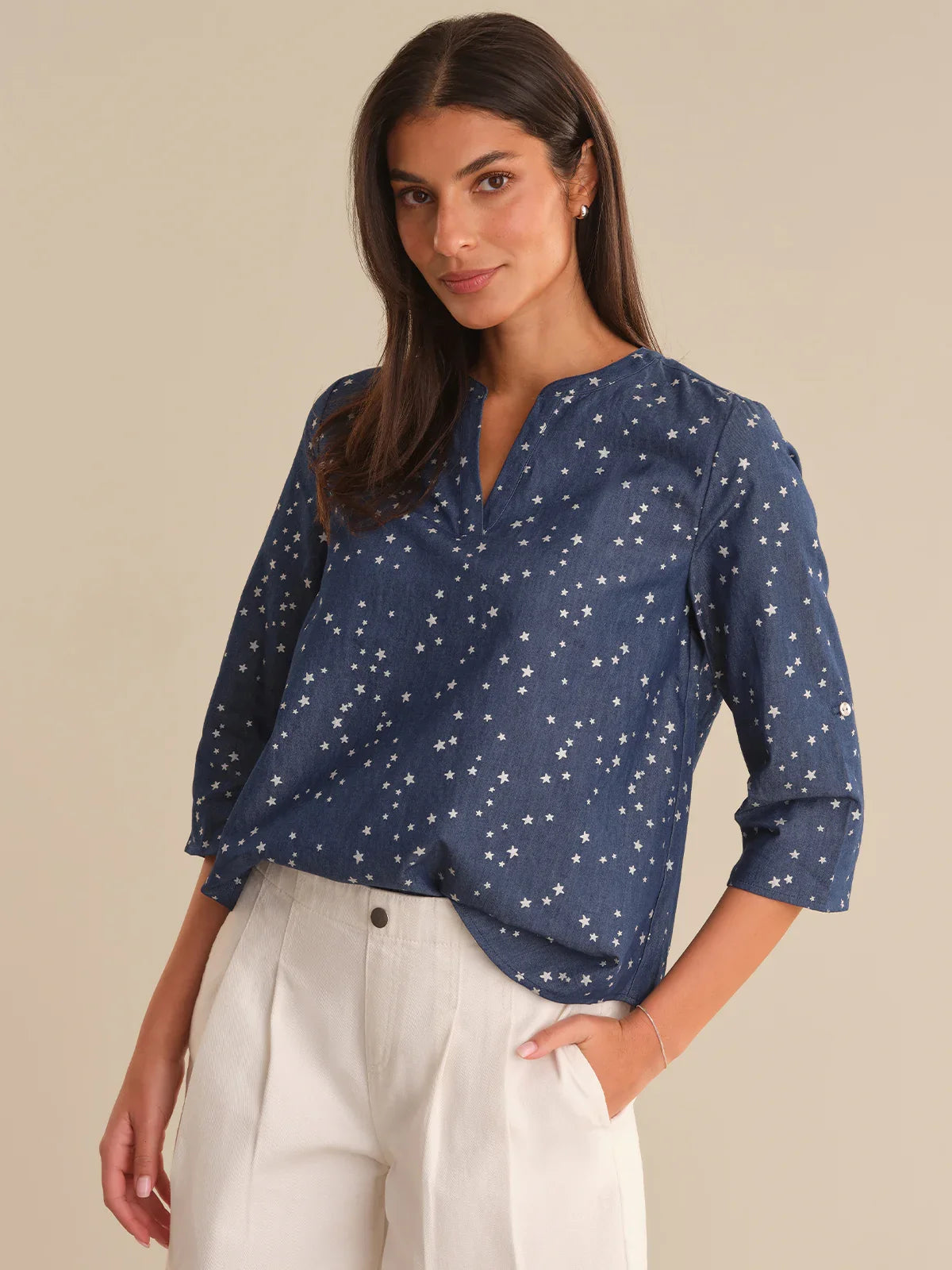 Woman wearing a blue star-patterned blouse against a beige background