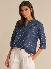 Woman wearing a blue star-patterned blouse against a beige background