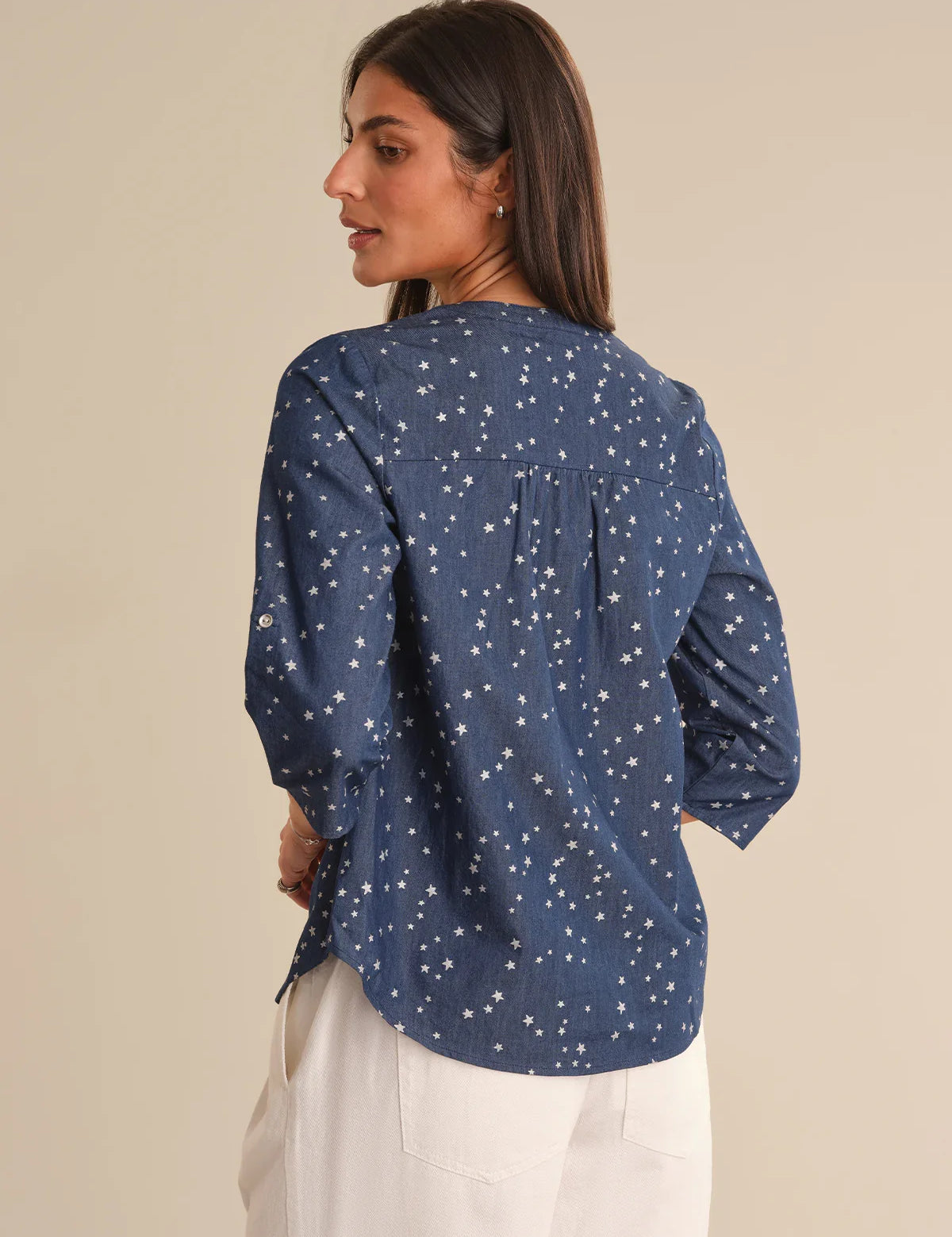 Woman wearing a blue patterned shirt against a beige background