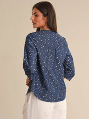 Woman wearing a blue patterned shirt against a beige background