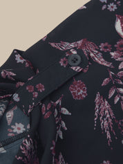Close-up of a dark floral garment detail showing a button closure, fabric texture, and a pink and white botanical print on a black base.
