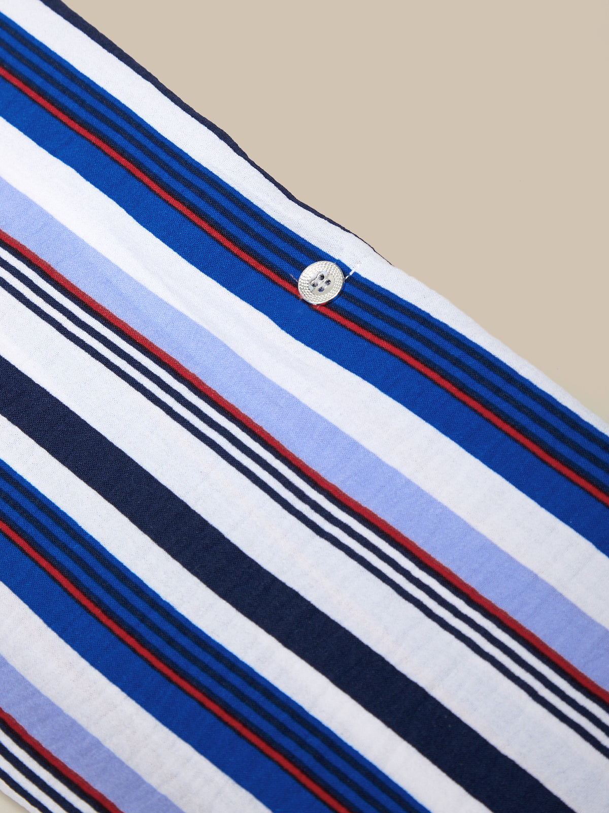 Close-up of a shirt with blue, white, and red stripes on a beige background