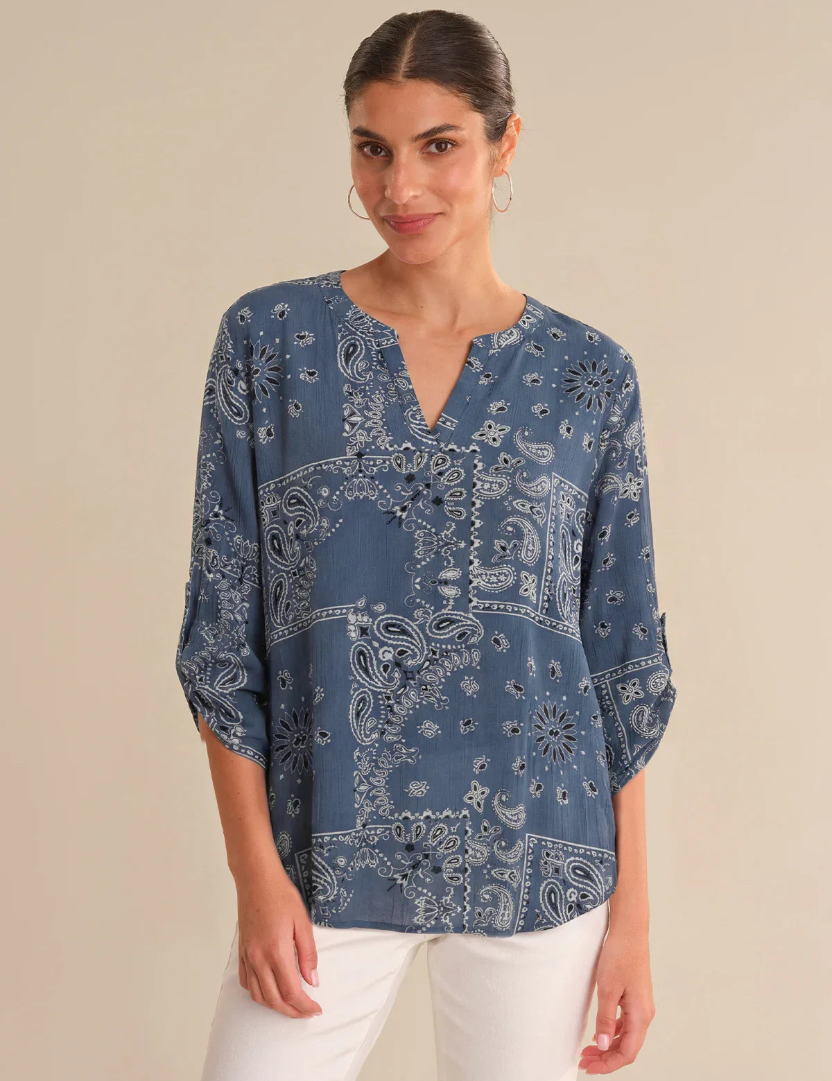 Woman wearing a blue paisley patterned blouse against a beige background
