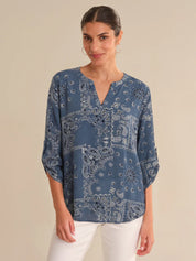 Woman wearing a blue paisley patterned blouse against a beige background