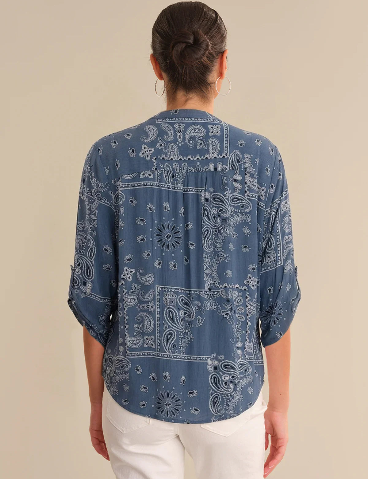 Person wearing a blue bandana print shirt on a beige background