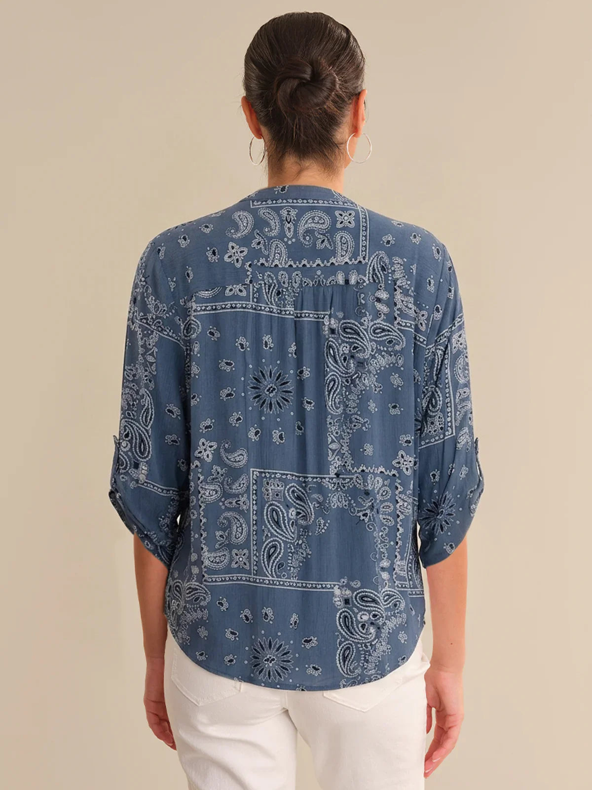 Person wearing a blue bandana print shirt on a beige background
