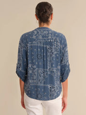 Person wearing a blue bandana print shirt on a beige background