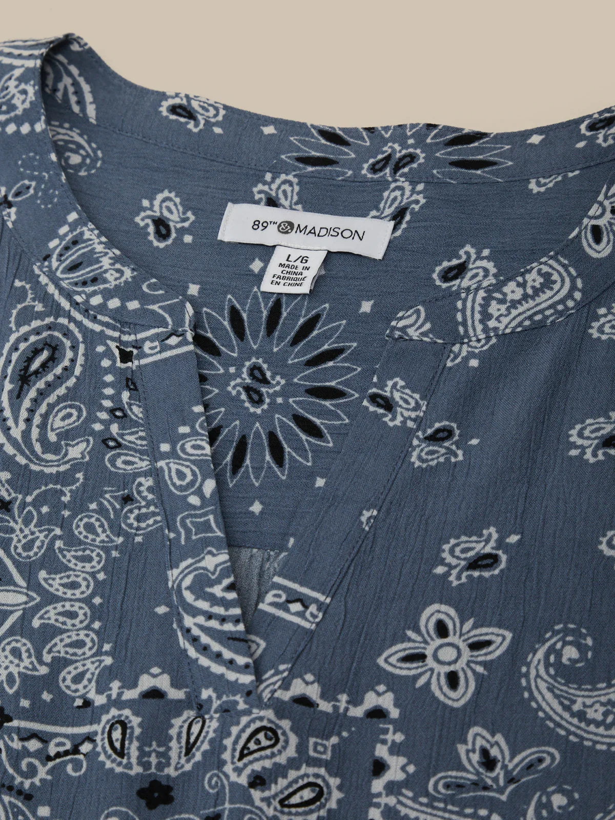 Blue bandana patterned fabric with a visible brand label on a beige background