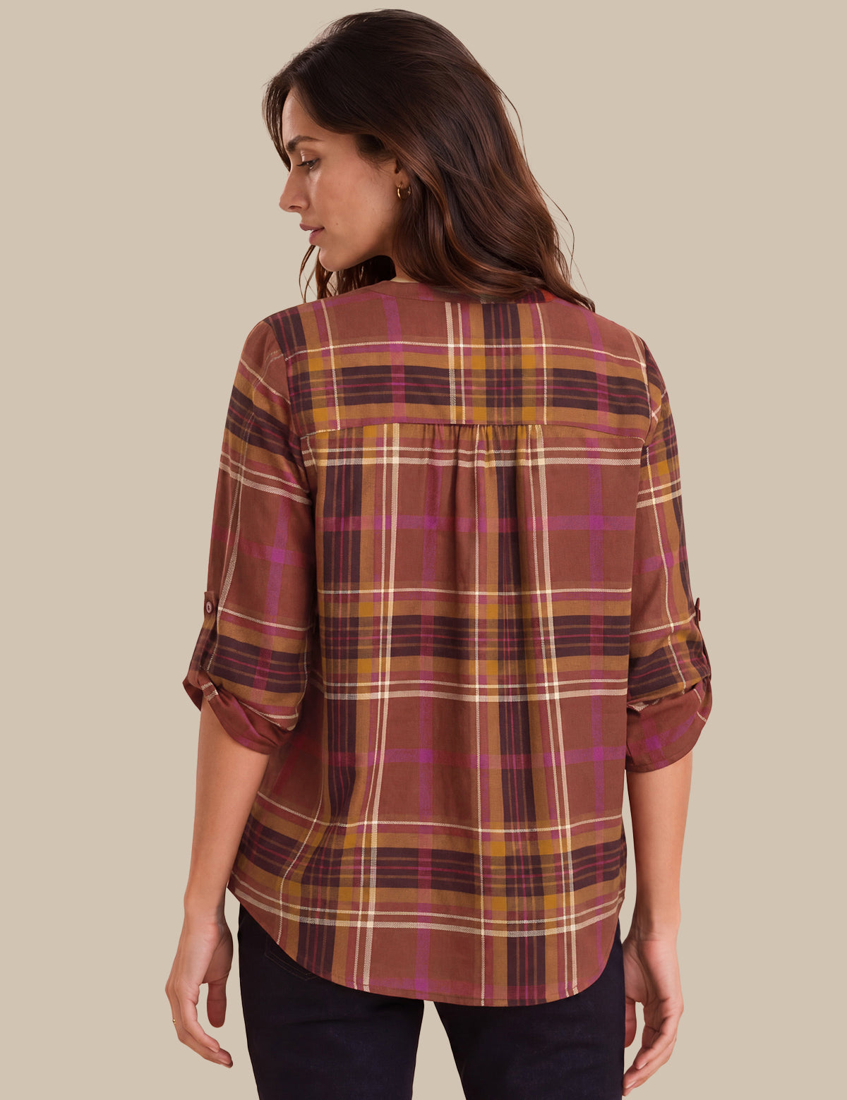 A woman shown from the back wearing a plaid button-up shirt with three-quarter sleeves, featuring a pattern of rust brown, mustard yellow, and magenta on a beige background.