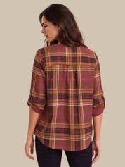 A woman shown from the back wearing a plaid button-up shirt with three-quarter sleeves, featuring a pattern of rust brown, mustard yellow, and magenta on a beige background.