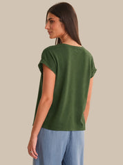 Woman wearing a green t-shirt and blue pants on a beige background