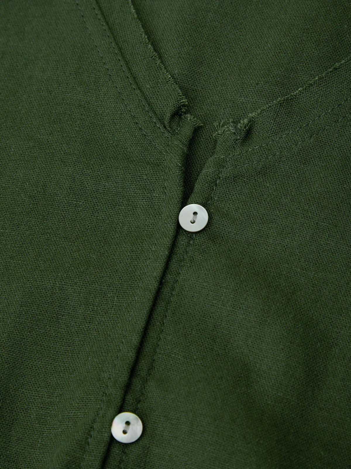 Close-up of a green shirt with buttons on a plain background