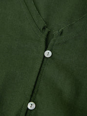 Close-up of a green shirt with buttons on a plain background