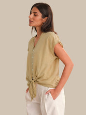 Woman wearing a green top with a plain background