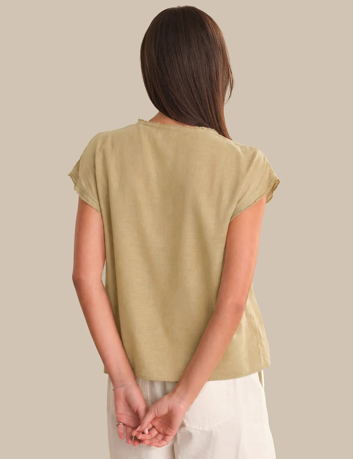 Person wearing a beige t-shirt against a plain background