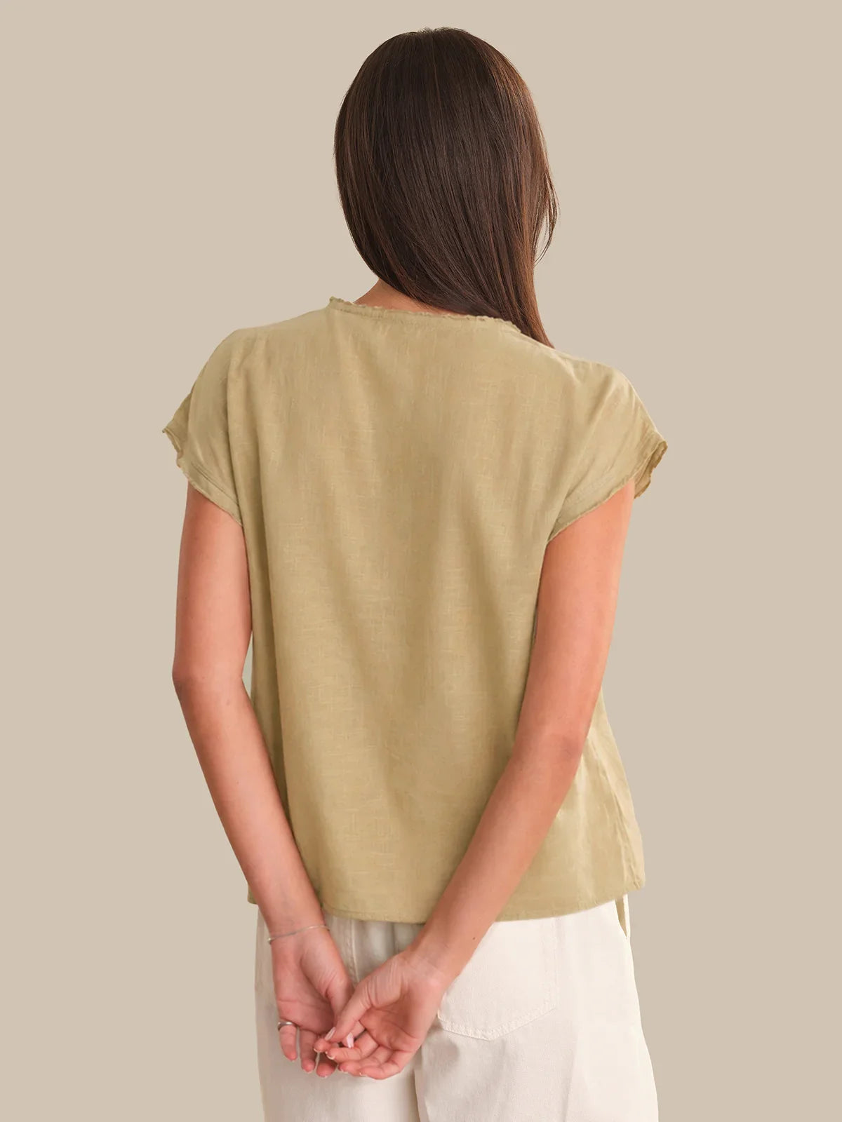 Person wearing a beige t-shirt against a plain background
