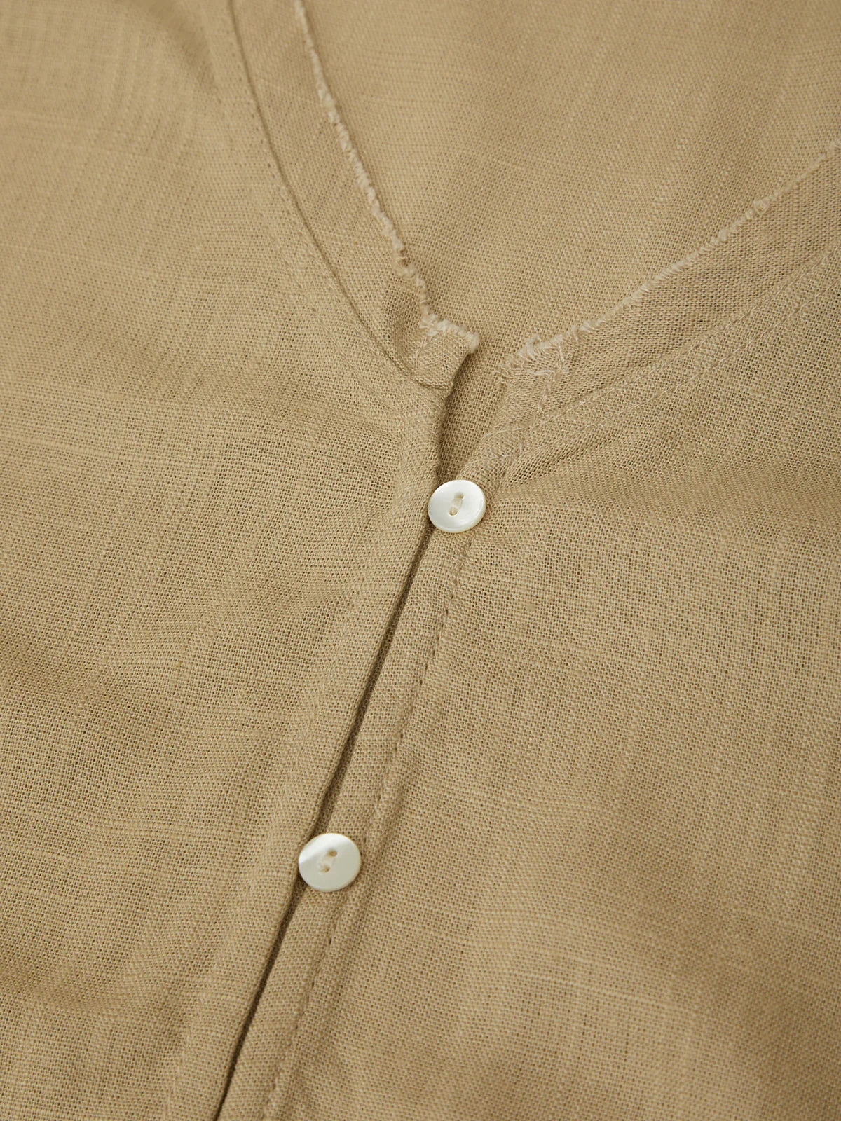 Close-up of a brown shirt with buttons on a textured fabric background