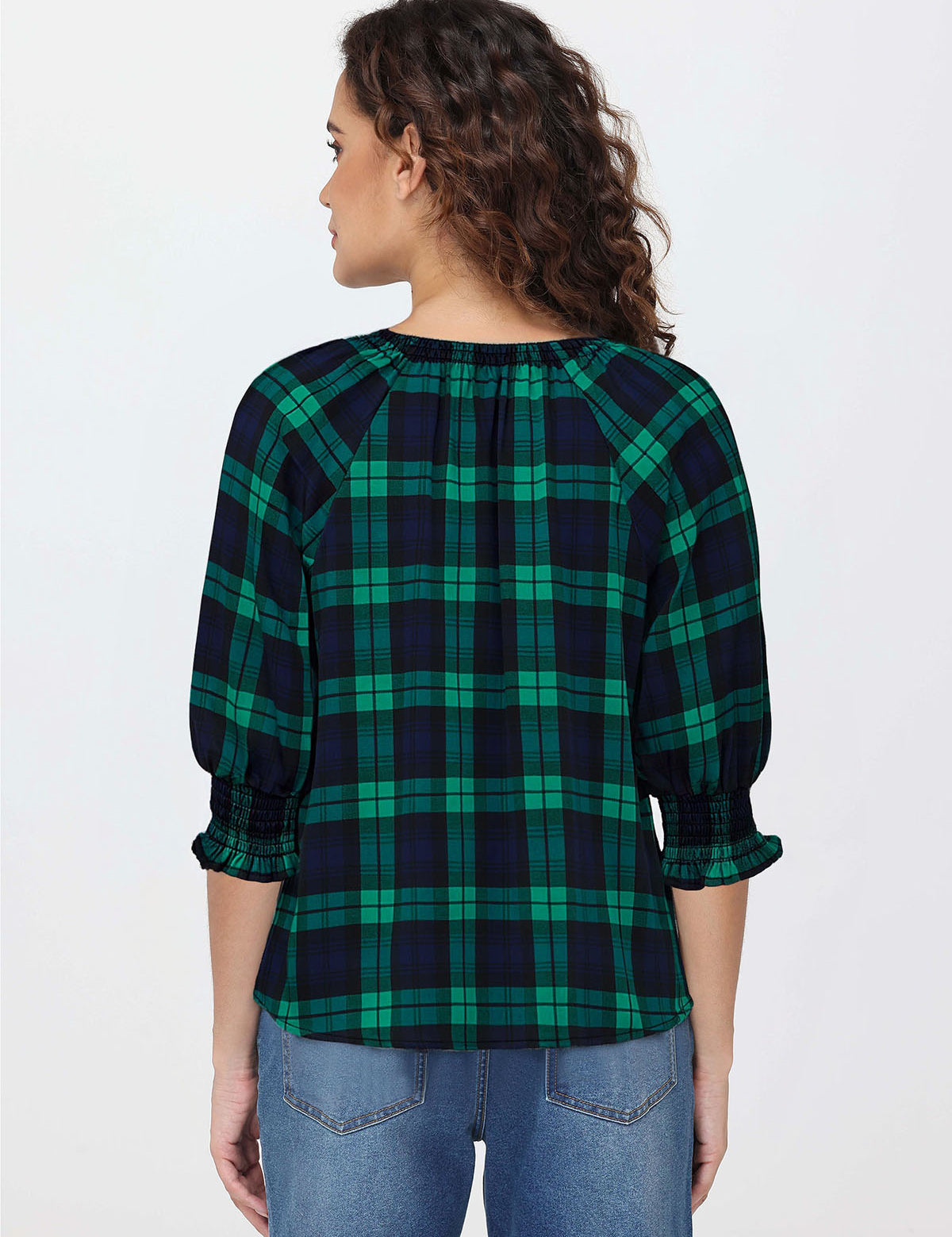 Woman wearing a green and navy plaid shirt on a white background