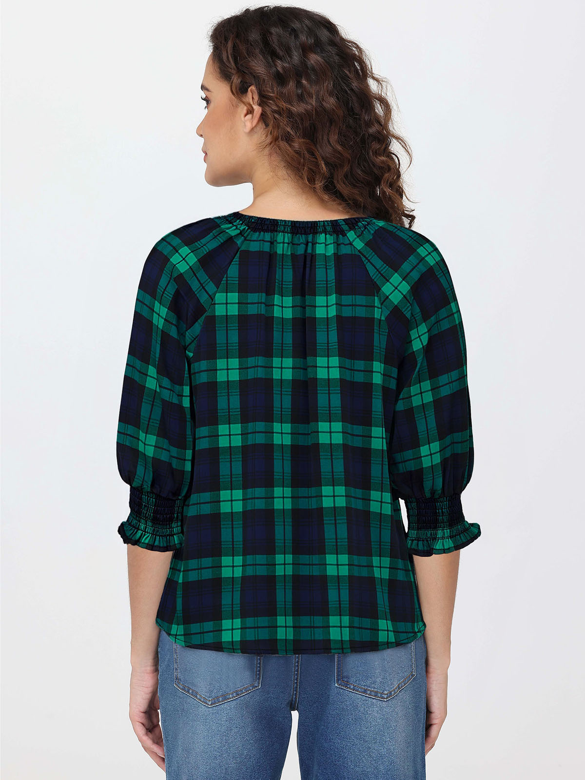 Woman wearing a green and navy plaid shirt on a white background