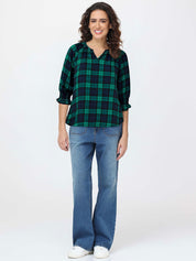 Woman wearing a green and black plaid shirt and blue jeans on a white background