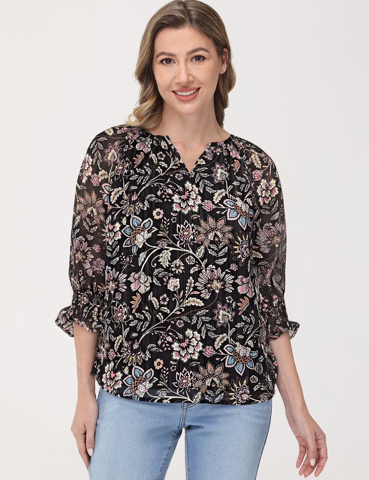 Woman wearing a black floral blouse with light blue jeans on a white background