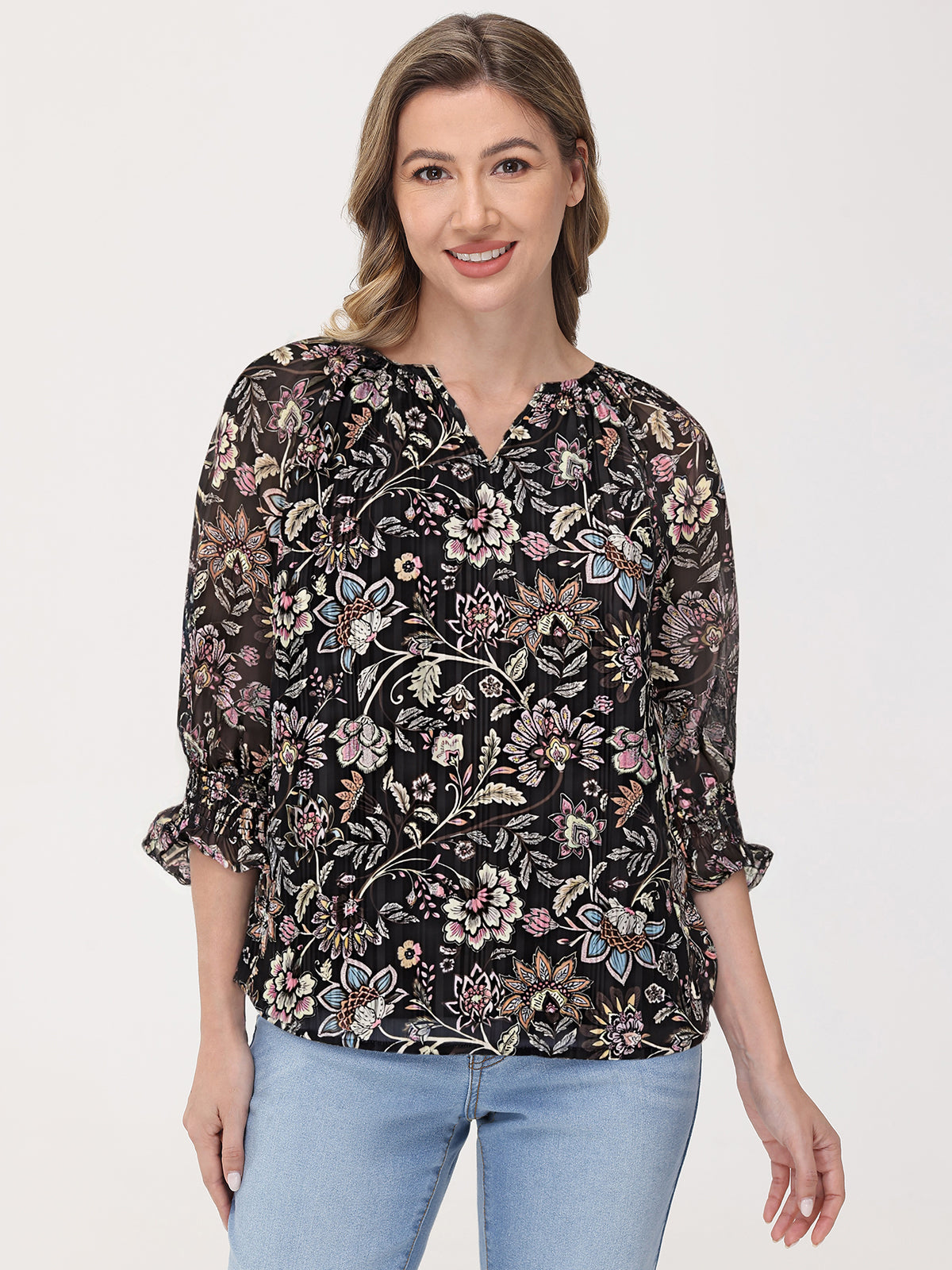 Woman wearing a black floral blouse with light blue jeans on a white background