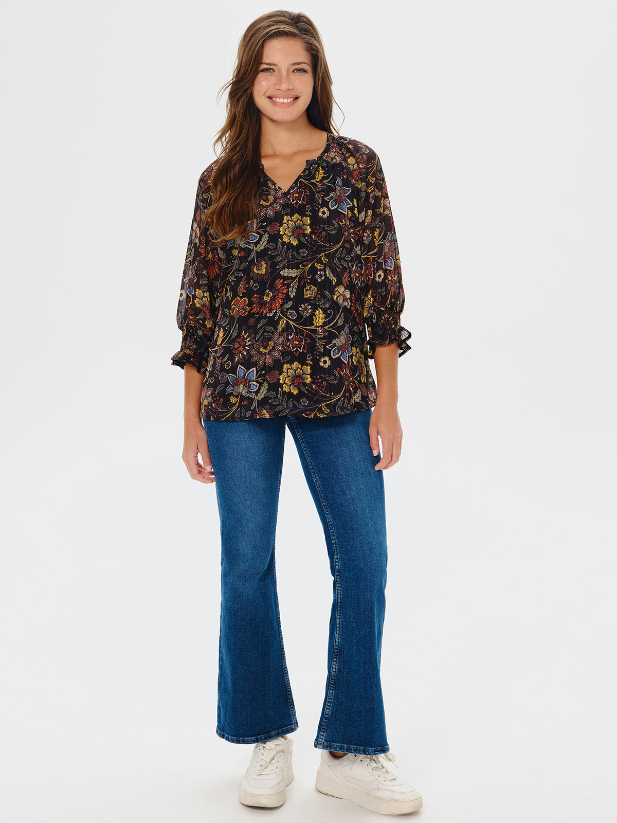 Woman wearing a floral blouse and blue jeans on a white background