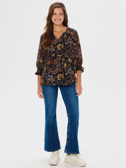Woman wearing a floral blouse and blue jeans on a white background