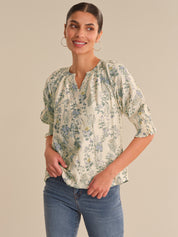 Woman wearing a floral blouse and jeans against a beige background