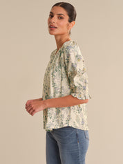 Woman wearing a floral blouse and jeans on a beige background