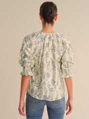 Woman wearing a floral blouse and blue jeans on a beige background
