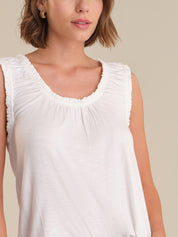 Woman wearing a white sleeveless top against a neutral background