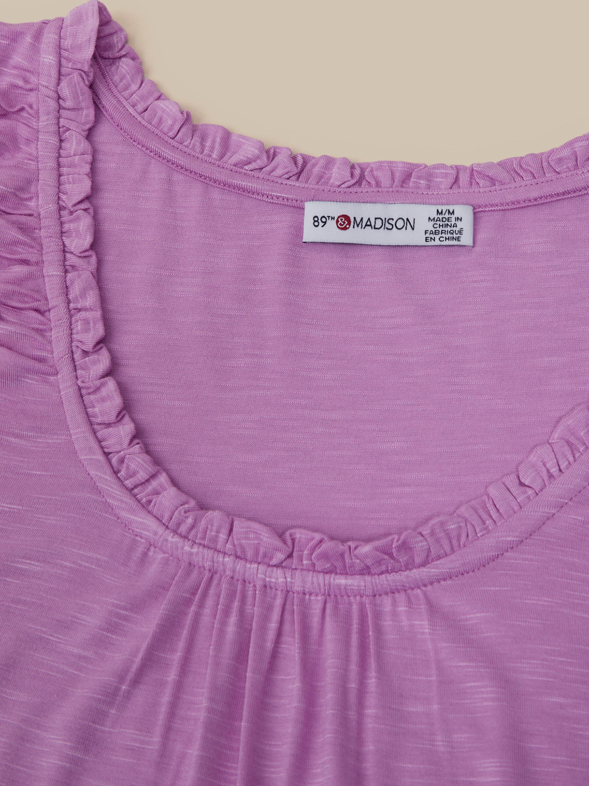 Close-up of a purple garment with a visible label on a beige background