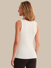 Woman wearing a white sleeveless top against a beige background
