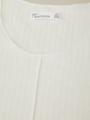 Close-up of a white garment with '89th + Madison' branding on a beige background