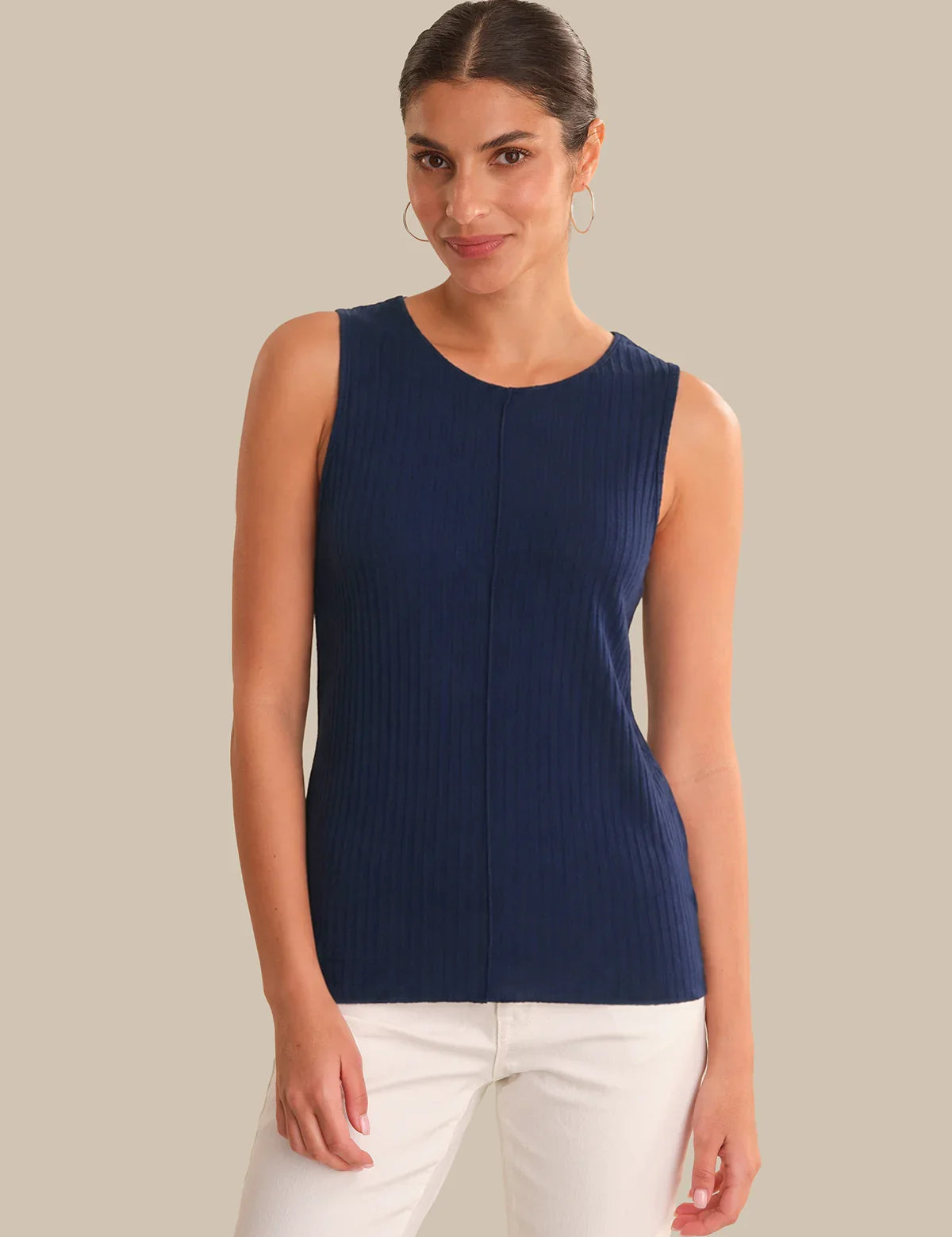 Woman wearing a navy sleeveless top against a beige background