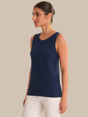 Woman wearing a navy sleeveless top against a beige background