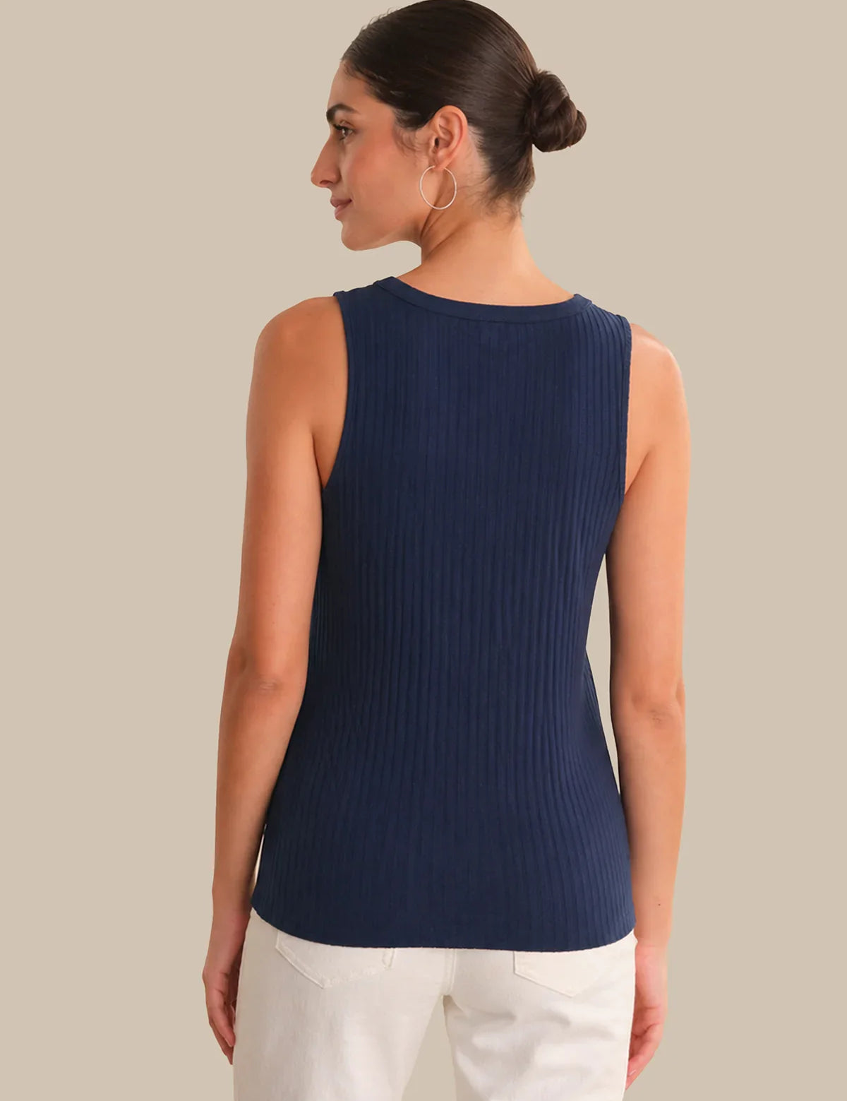 Woman wearing a navy ribbed tank top against a beige background