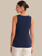 Woman wearing a navy ribbed tank top against a beige background